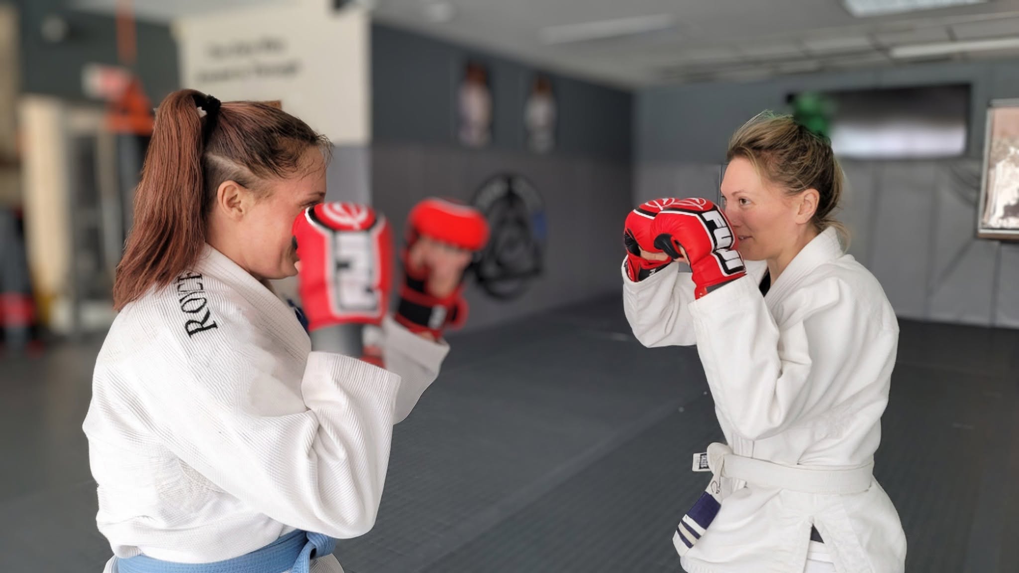 Two women practicing striking defense with gloves